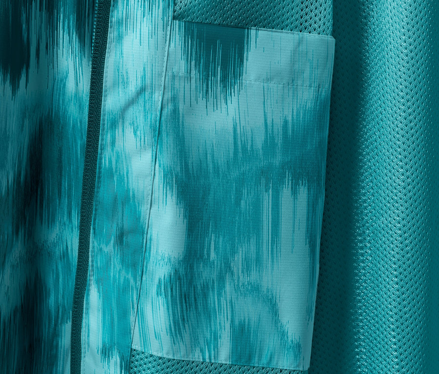 Detal kurtki przeciwdeszczowej z nadrukiem i kieszenią.