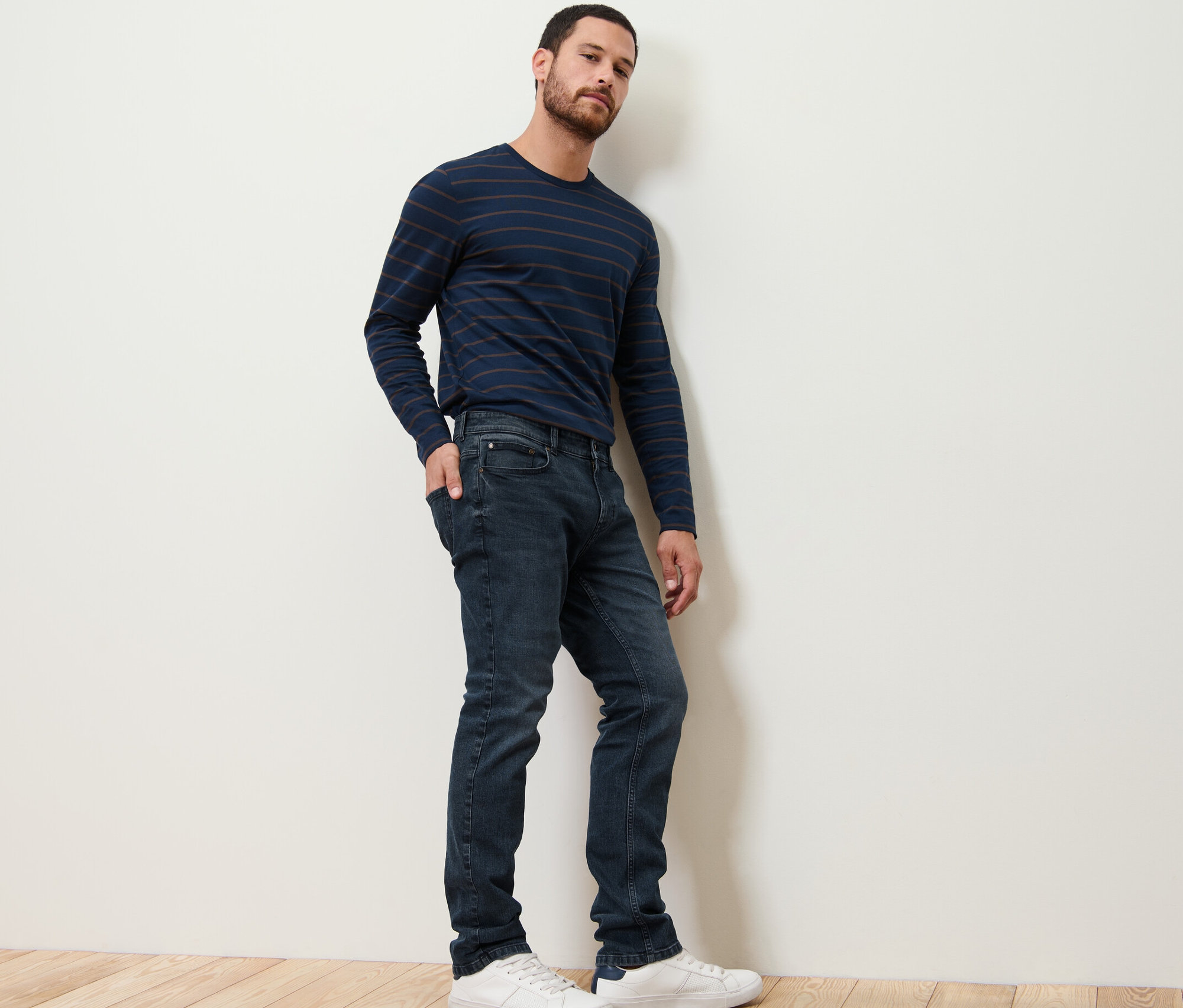 Mężczyzna pozuje w dżinsach i koszulce w paski.