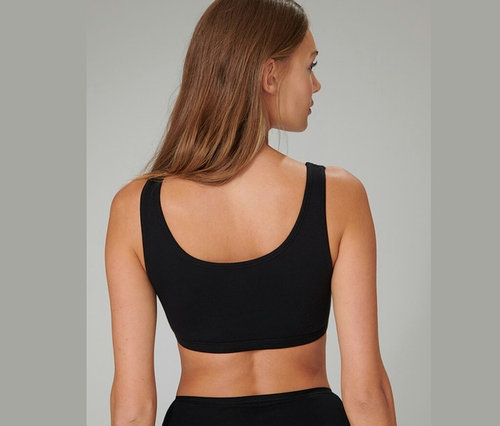 Widok z tyłu na kobietę z brązowymi włosami, ubraną w czarne braletki z bawełną ekologiczną SCHIESSER, 2 sztuki.