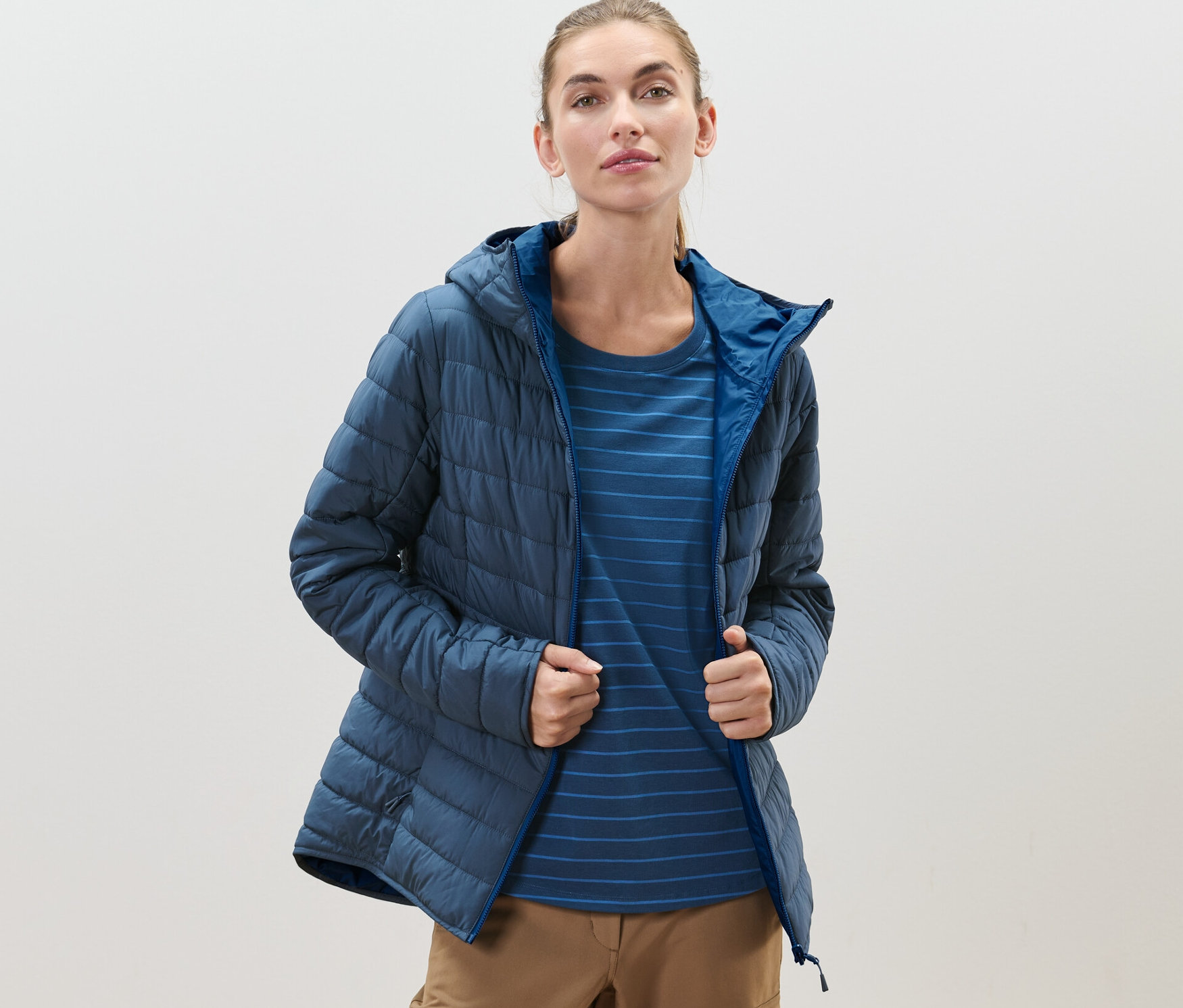 Kobieta ma na sobie niebieską, nieprzemakalną, dwustronną kurtkę pikowaną.