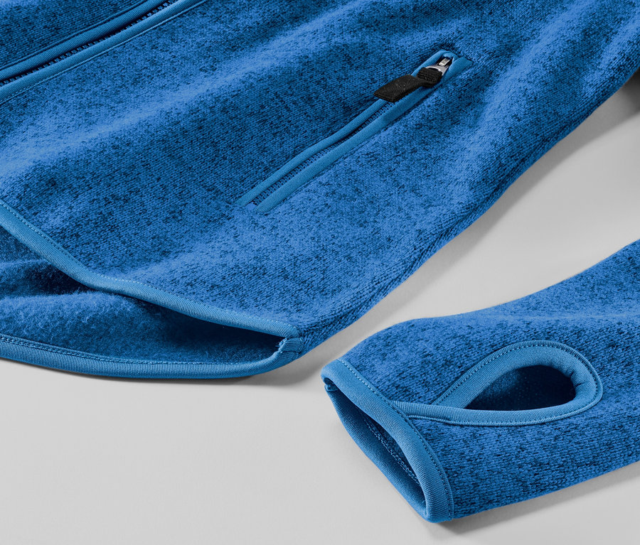 Zbliżenie na niebieską rozpinaną bluzę z dzianiny polarowej z kieszenią na zamek i otworem na kciuk.