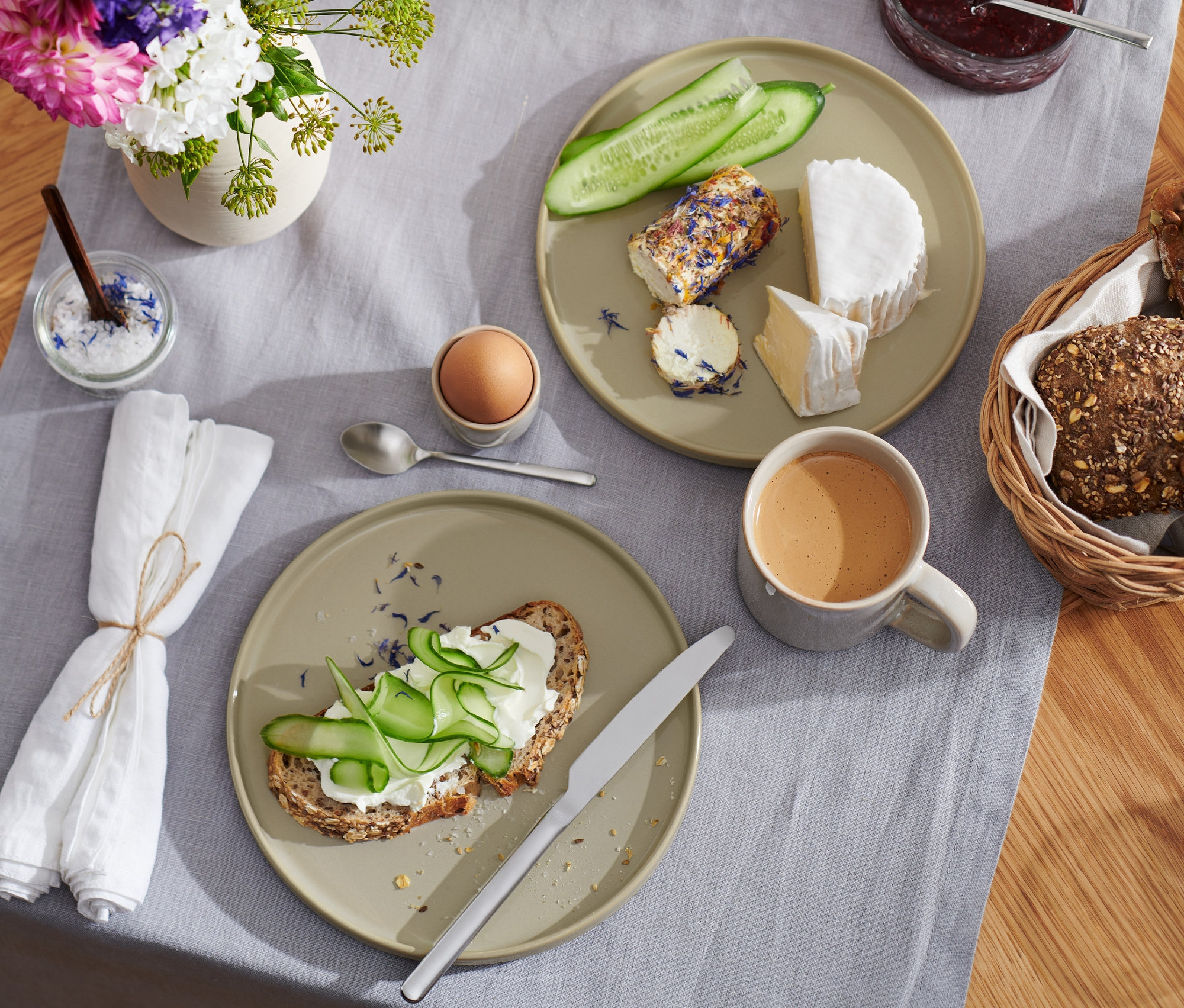 Śniadanie na stole z talerzami, 2 sztuki, 21 cm, chlebem, serem, warzywami, jajkiem, kawą i sokiem.