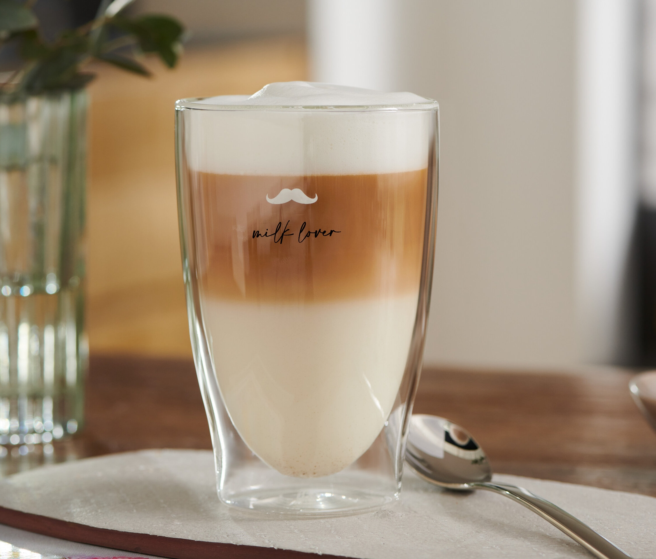 Warstwowe latte macchiato w szklance z nadrukiem wąsów.