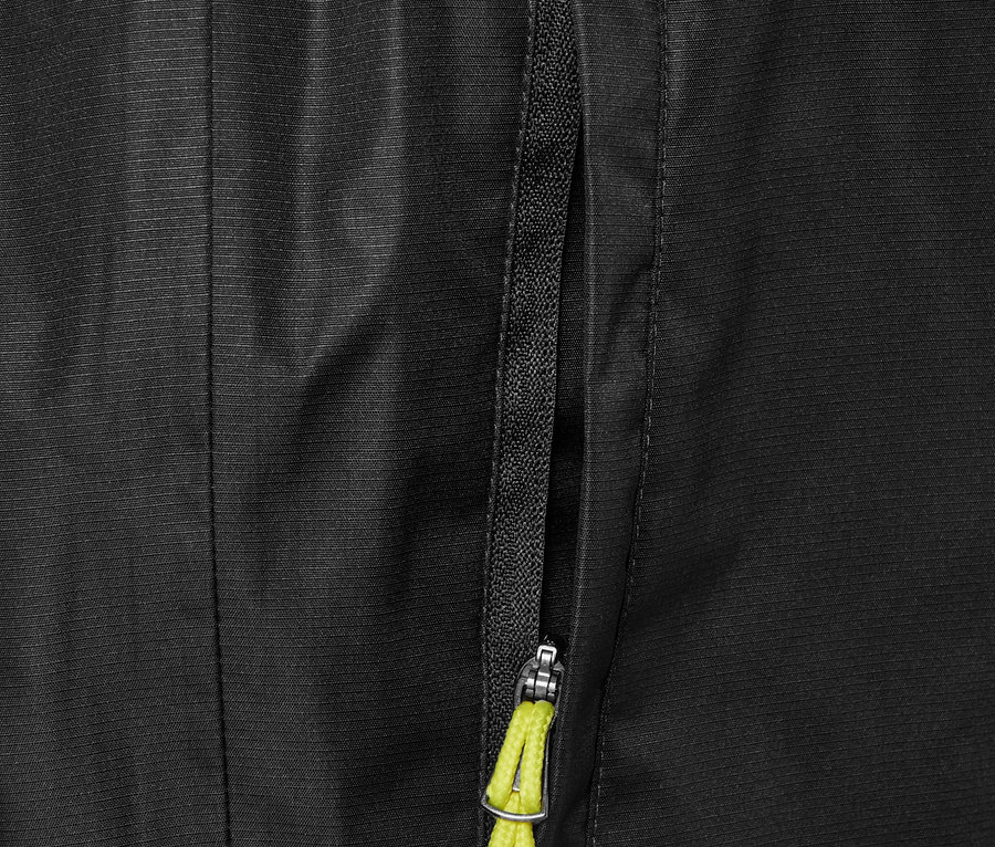 Zbliżenie na czarne spodnie przeciwdeszczowe z kieszenią na zamek i żółtym sznurkiem.