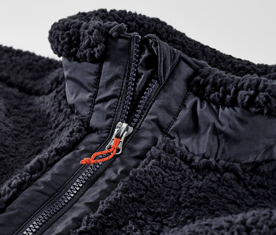 Zbliżenie na rozpiętą kamizelkę z pluszu z zamkiem błyskawicznym.