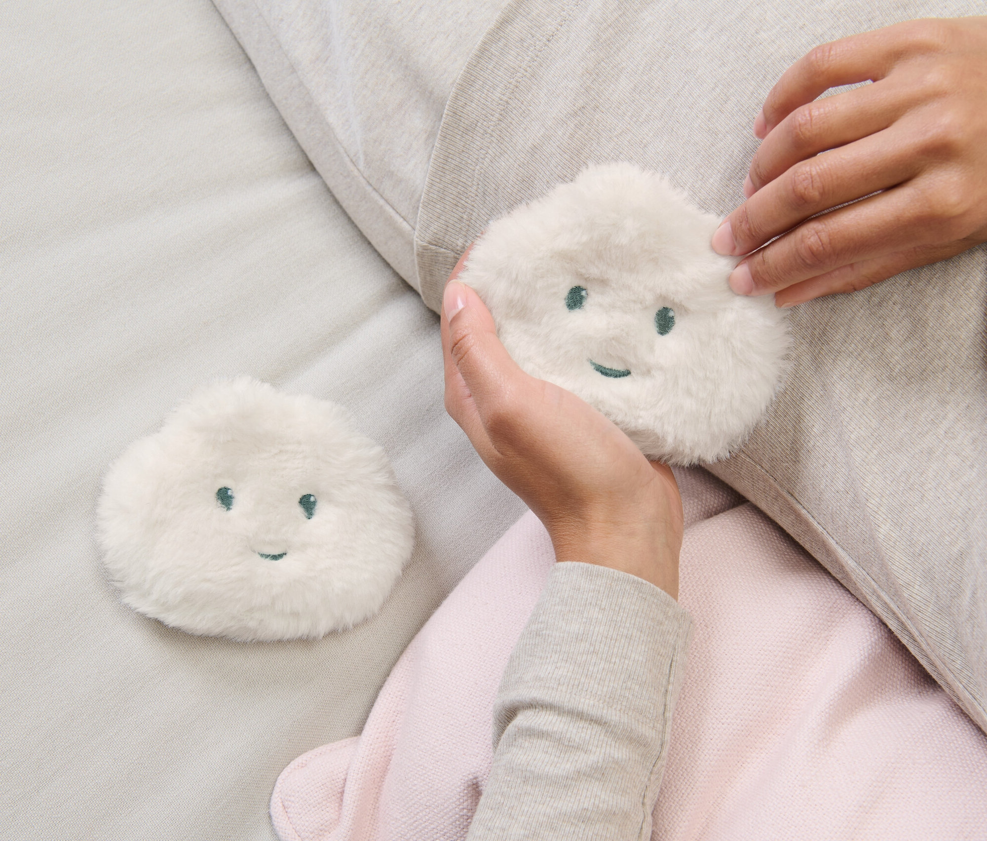 Kobieta trzyma w dłoni jeden z dwóch kieszonkowych ogrzewaczy dłoni.