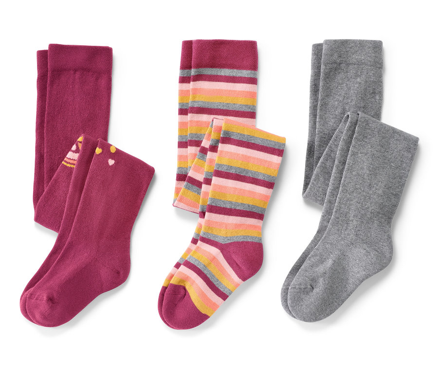 Na białym tle leżą trzy pary różowych rajstop dziecięcych.