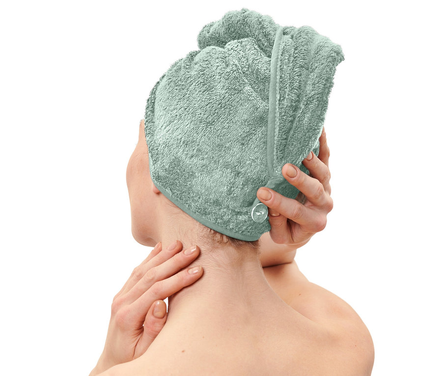 Kobieta zakłada jasnoniebieski ręcznik turban.