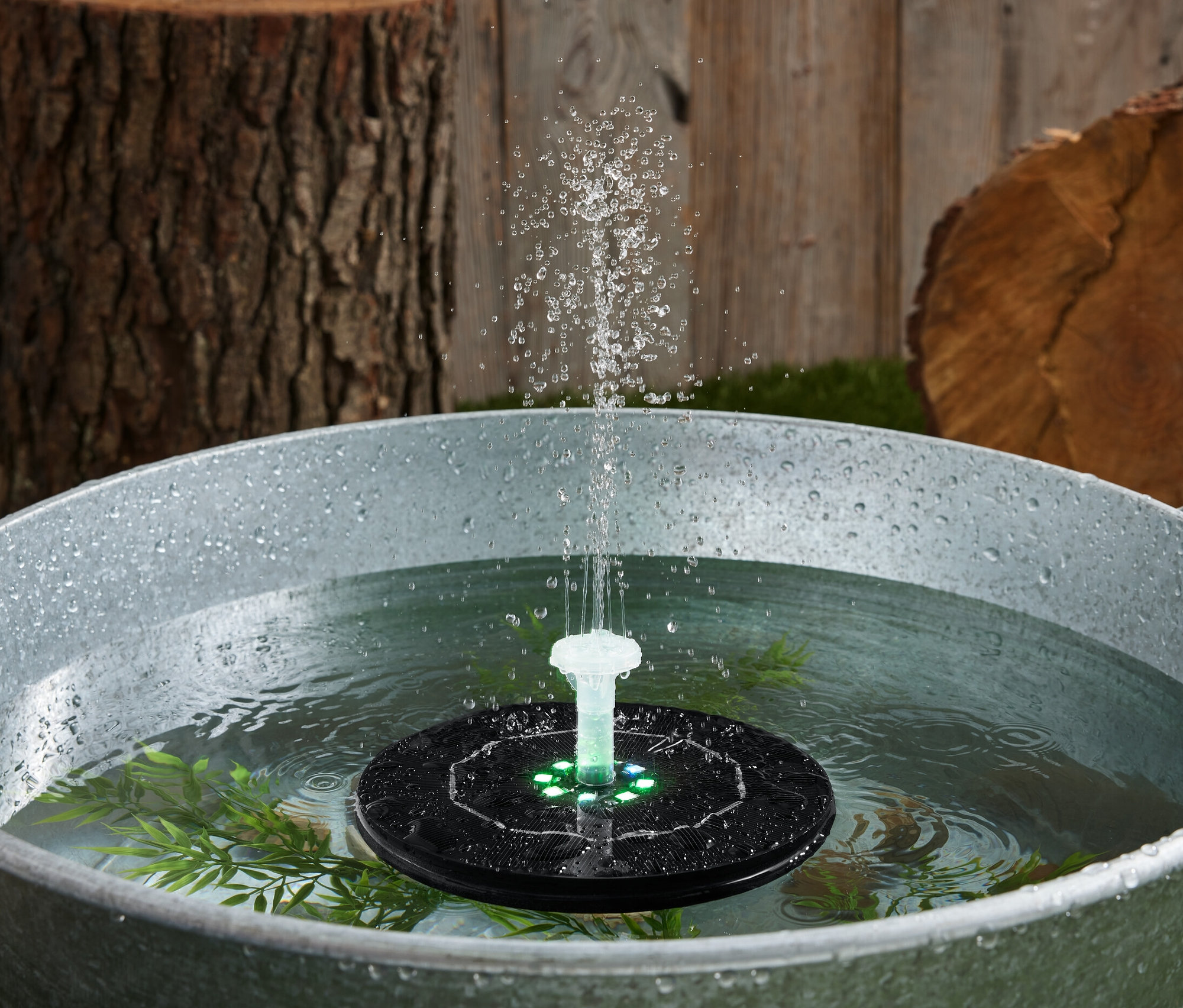 Pływająca fontanna solarna z podświetleniem w wannie z wodą.