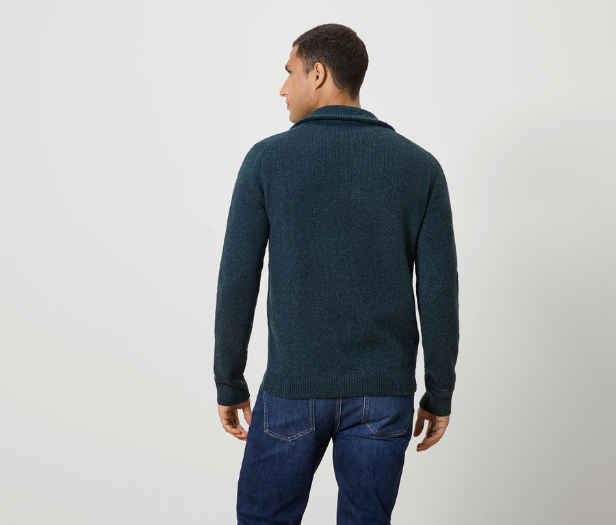 Mężczyzna od tyłu, ubrany w granatowy sweter i dżinsy.