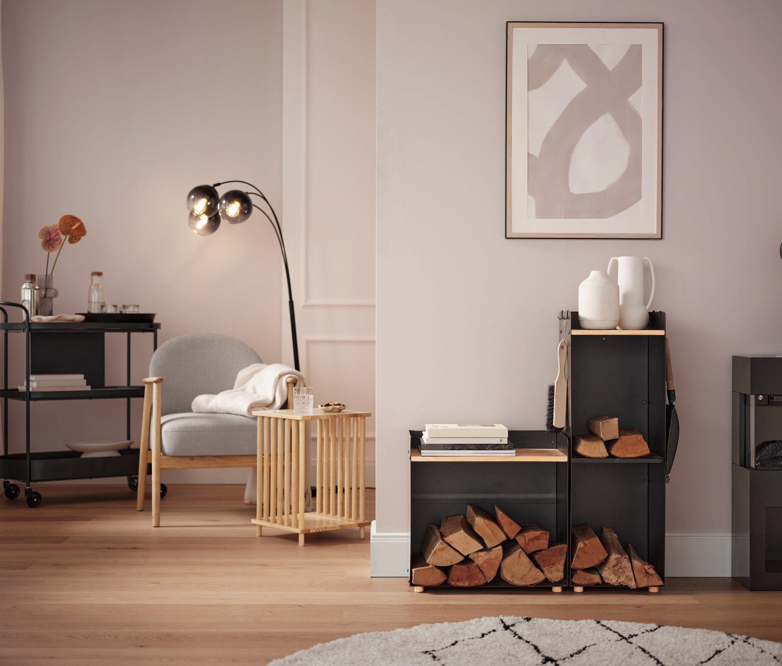 Salon z szarym fotelem, lampą podłogową i wózkiem na kółkach.