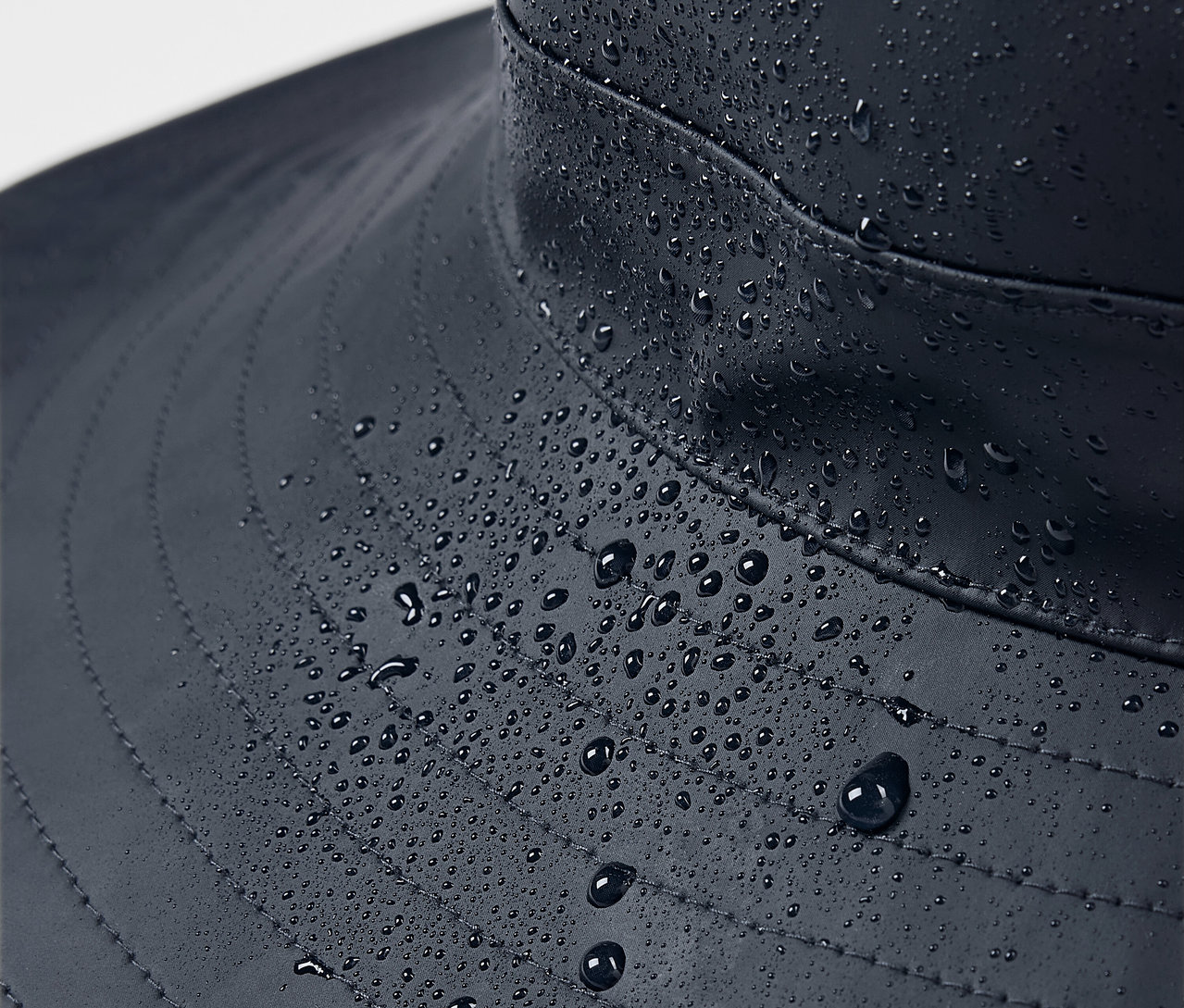 Zbliżenie na niebieski kapelusz przeciwdeszczowy z kroplami wody.