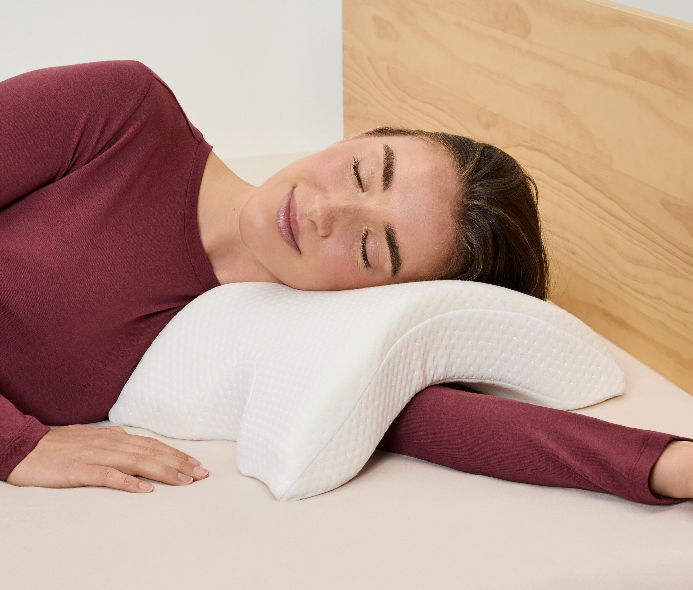 Kobieta leży na boku na białej poduszce.