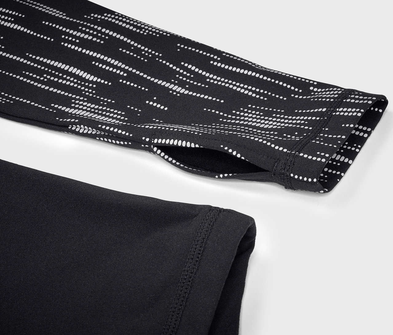 Zbliżenie czarnej koszulki sportowej z długim rękawem i białym geometrycznym wzorem na rękawie.