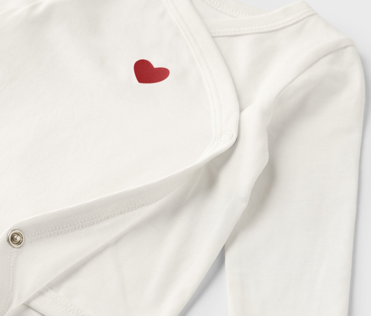 Zbliżenie na białe body rosnące z dzieckiem z czerwonym sercem.