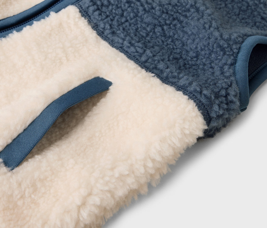 Szczegół niebiesko-beżowej kamizelki polarowej z kieszenią.