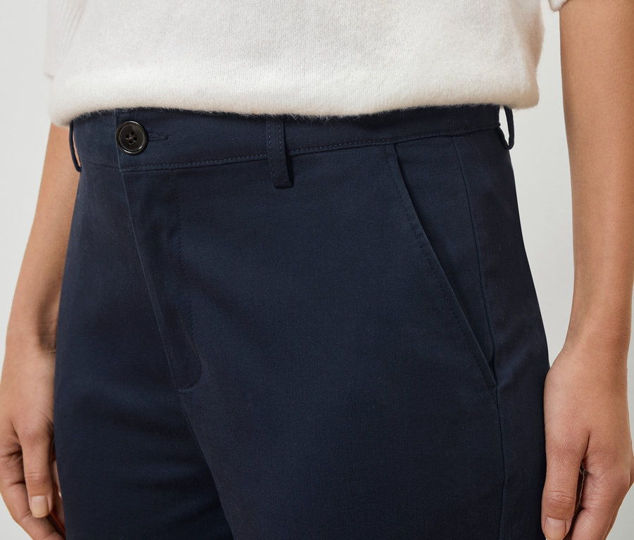 Zdjęcie z bliska osoby ubranej w granatowe spodnie i biały sweter.