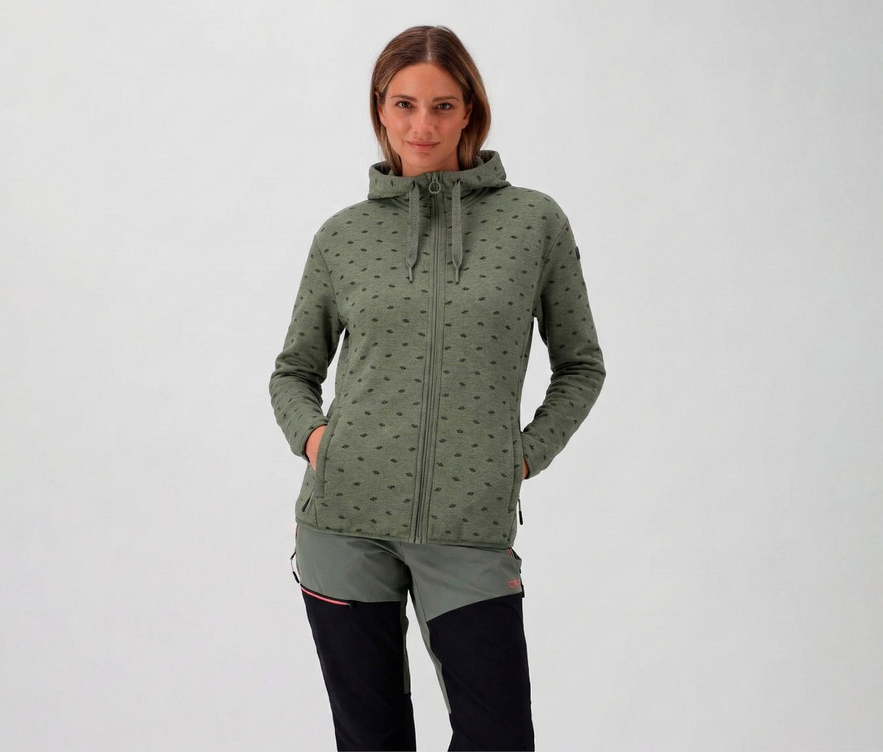 Kobieta w kapturze ma na sobie bluzę polarową CMP z kapturem, awokado i trzyma ręce w kieszeniach.