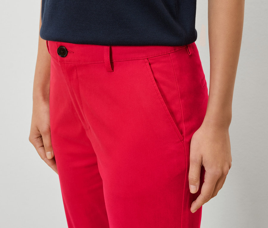 Zbliżenie kobiety w czerwonych spodniach i niebieskiej koszuli.