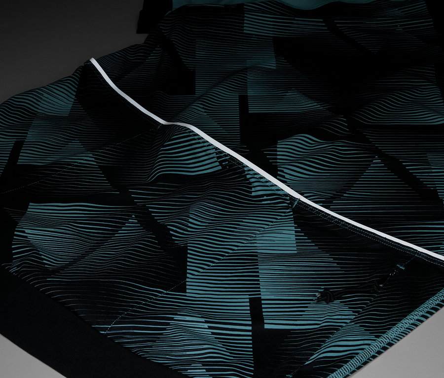 Zbliżenie ubrania ze wzorem geometrycznym w kolorze czarnym i turkusowym, podkreślonym białym paskiem.