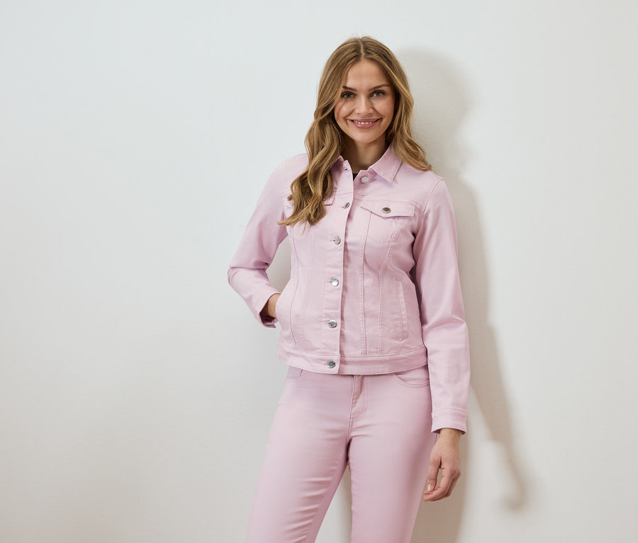 Kobieta ma na sobie różową kurtkę dżinsową i pasujące dżinsy.