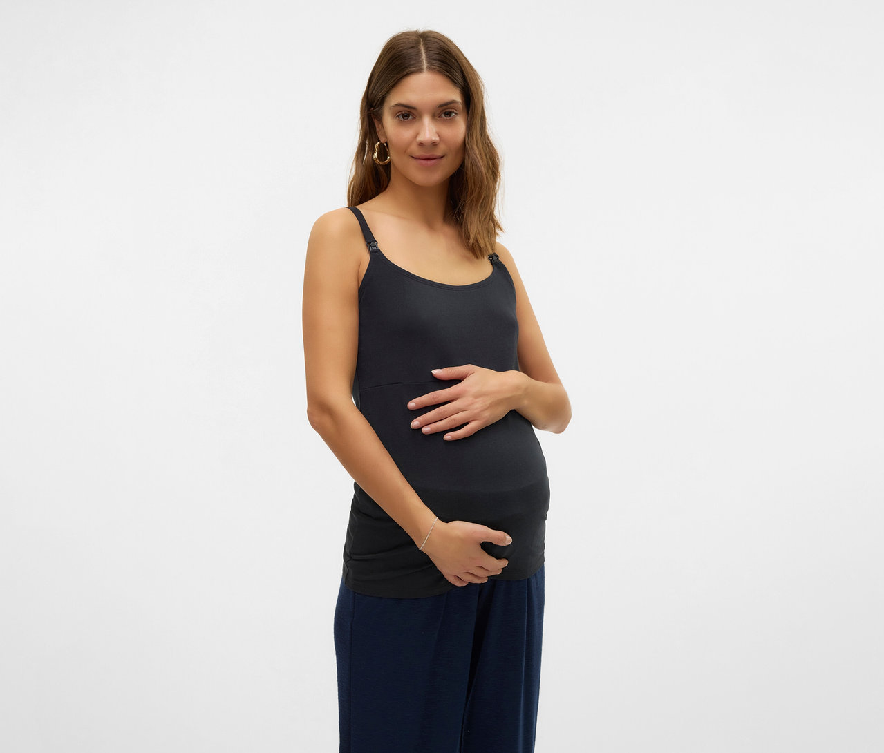 Kobieta w ciąży trzyma się za brzuch, ubrana w koszulkę na ramiączkach MAMALICIOUS „MLKERRIE”, 2 sztuki.