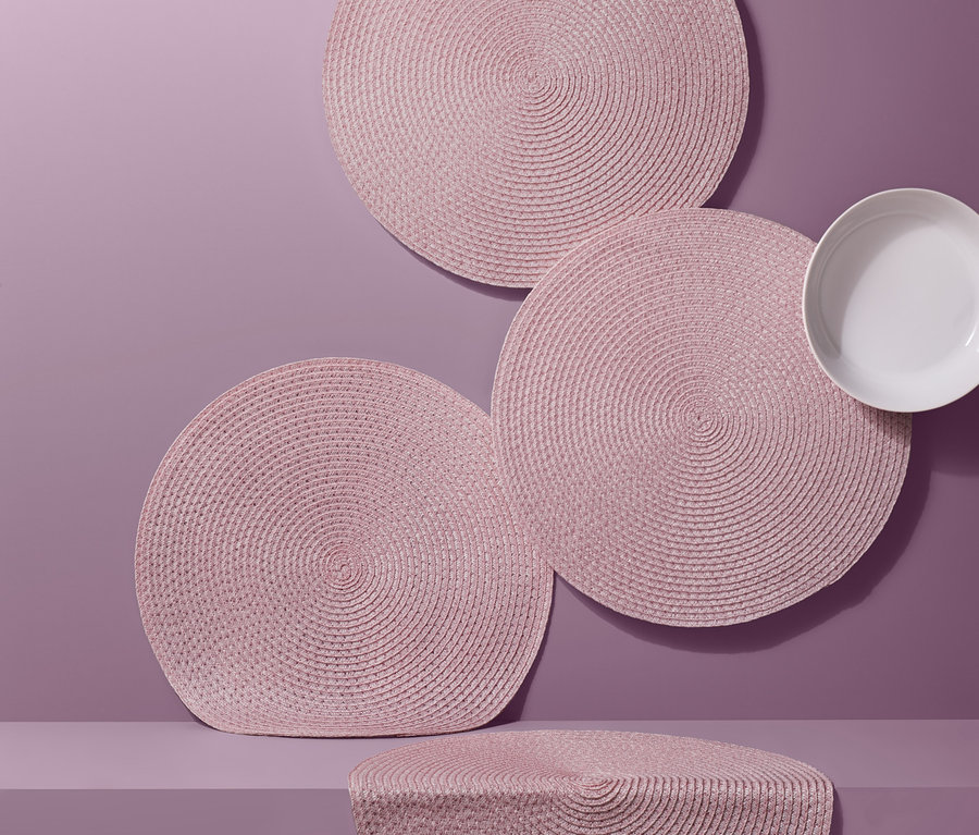 Różowe okrągłe podkładki pod talerze, 4 sztuki, ułożone z talerzem na fioletowym tle.