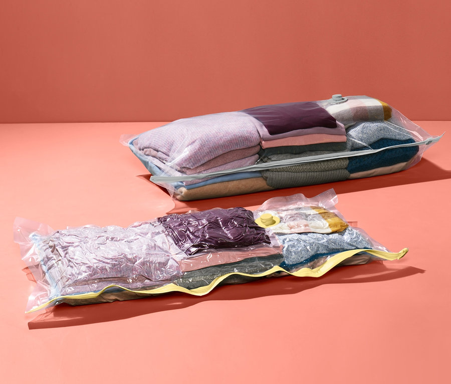 Dwa próżniowe worki do przechowywania z ubraniami na koralowym tle.