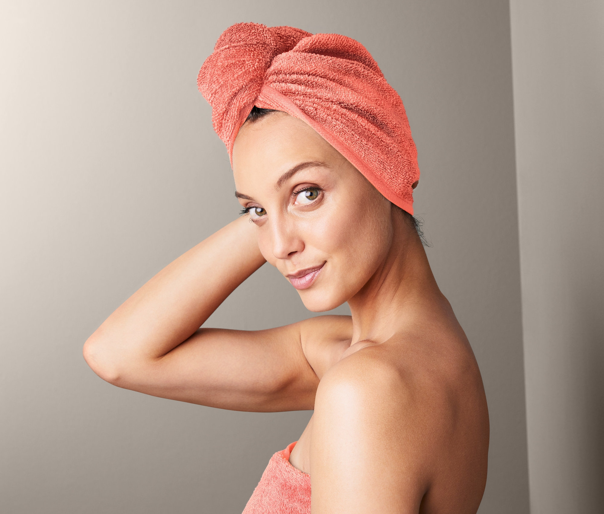 Kobieta z ręcznikiem z turbanem na głowie i ręcznikiem owiniętym wokół ciała.