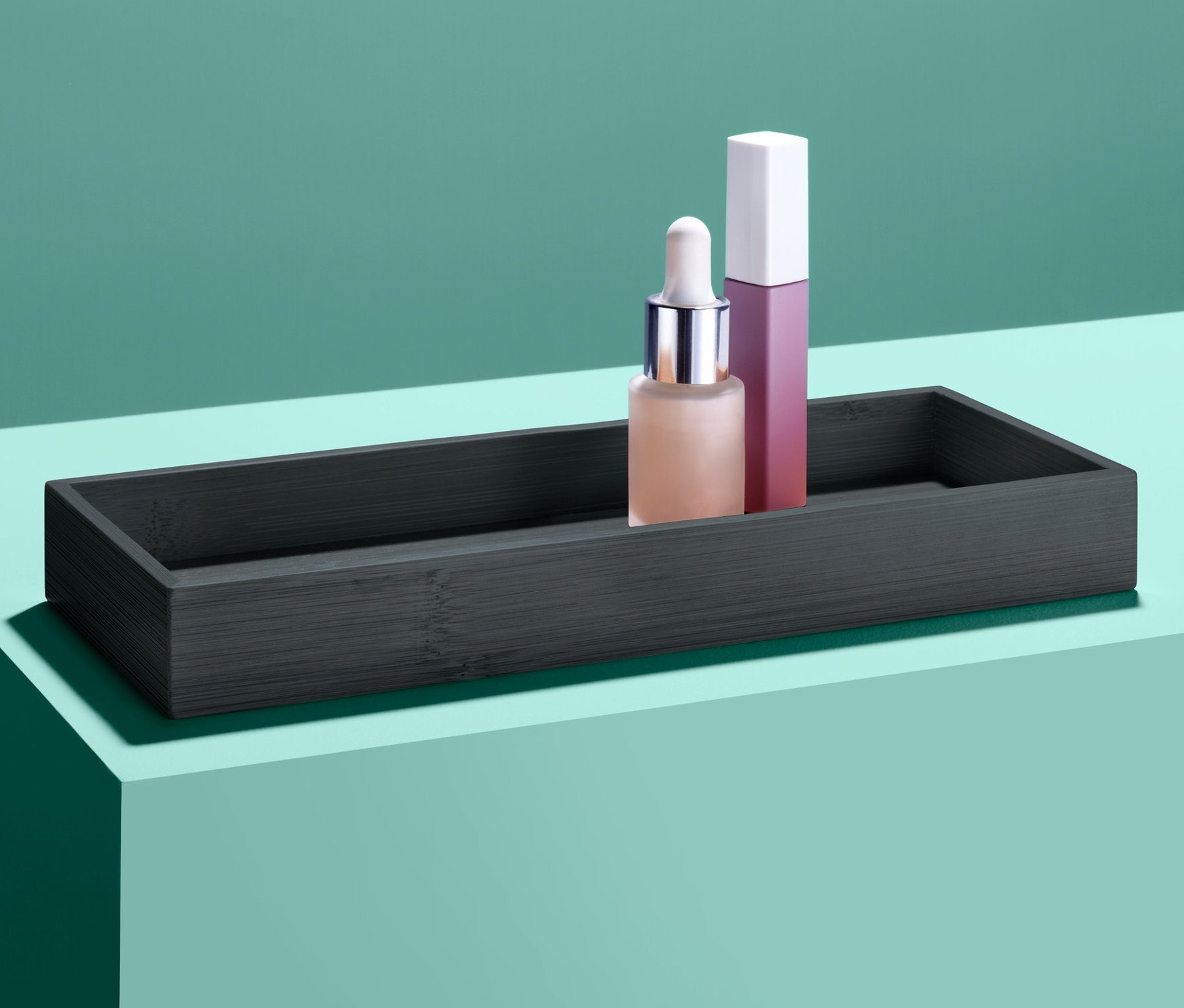 Kosmetyki w czarnej tacy na turkusowej powierzchni.