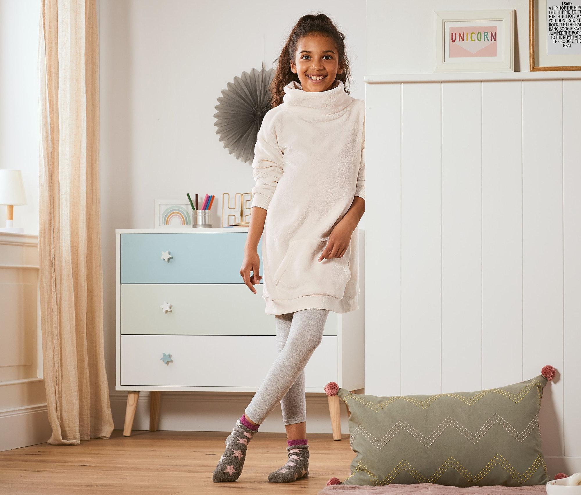 Dziewczyna stoi w pokoju i ma na sobie sukienkę rekreacyjną z materiału z recyklingu.