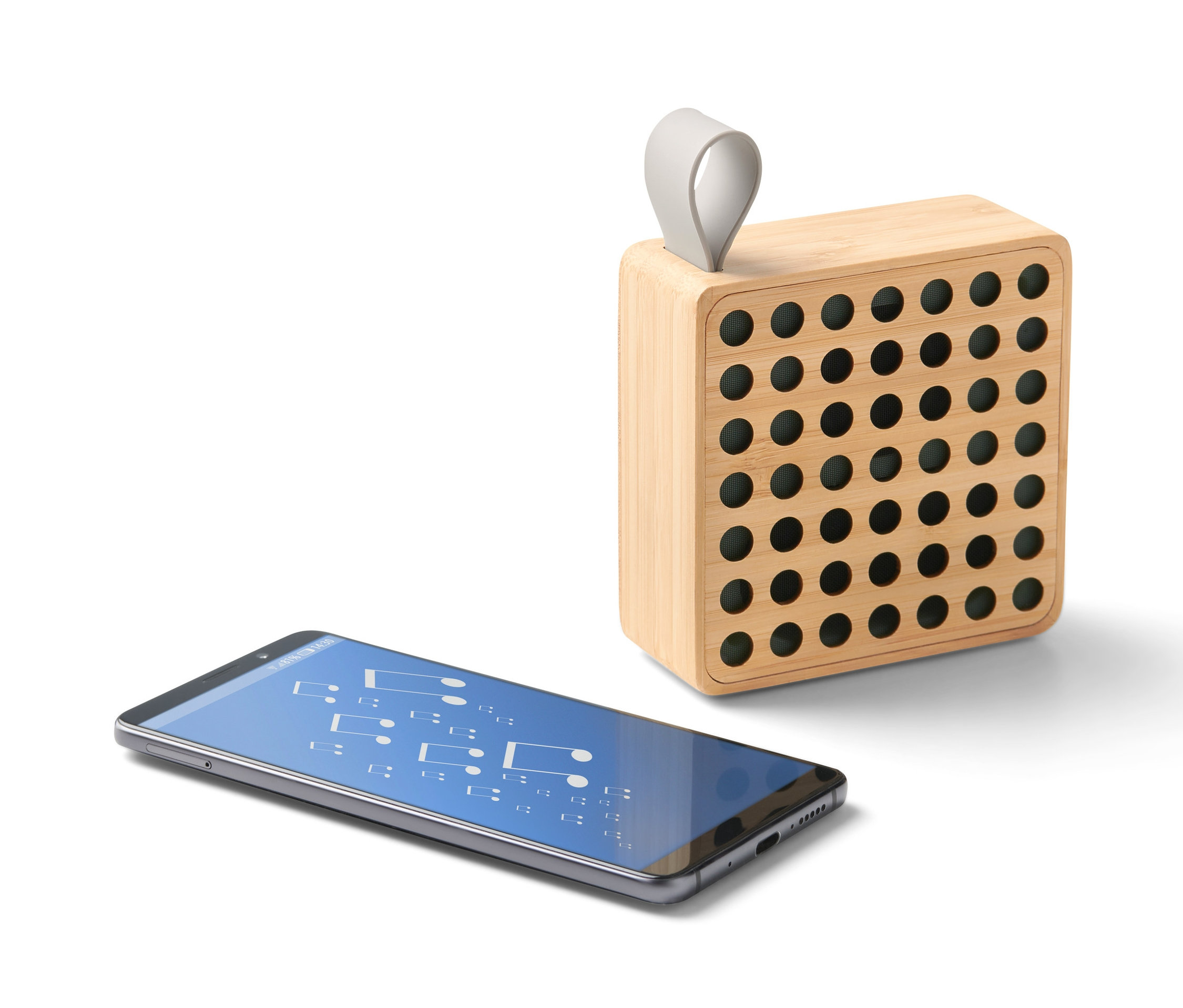 Bambusowy głośnik Bluetooth® obok smartfona.