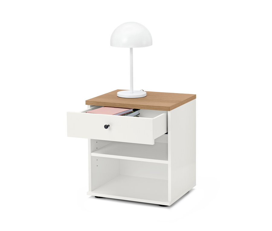 Biały stolik nocny »Bekeson« z brązowym blatem i otwartą szufladą. Na stoliku stoi biała lampa.