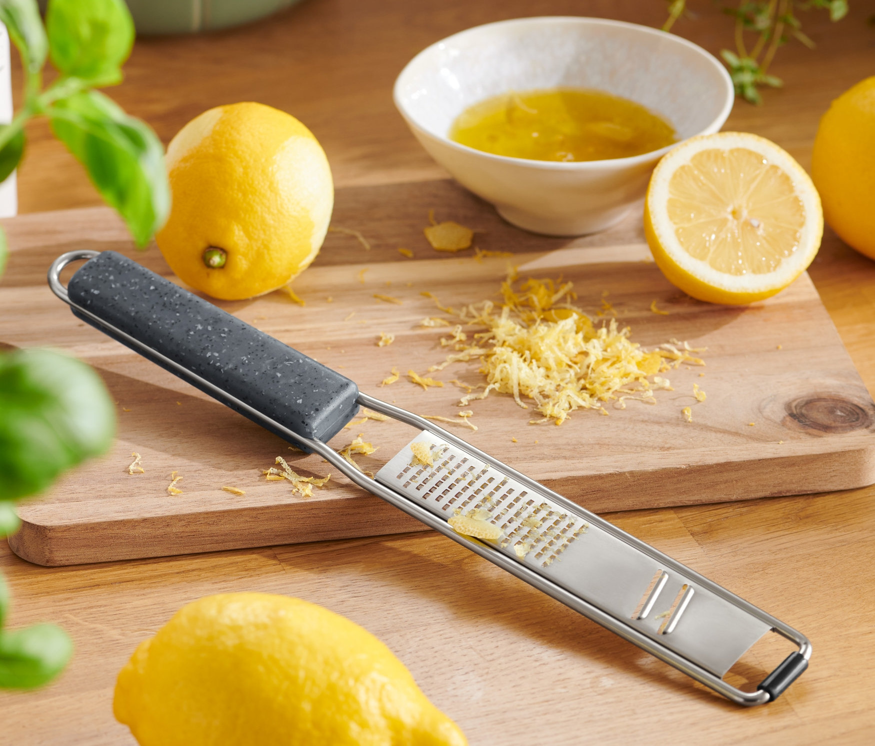 Tarka ręczna 2 w 1 leży na drewnianej desce z cytrynami i skórką.