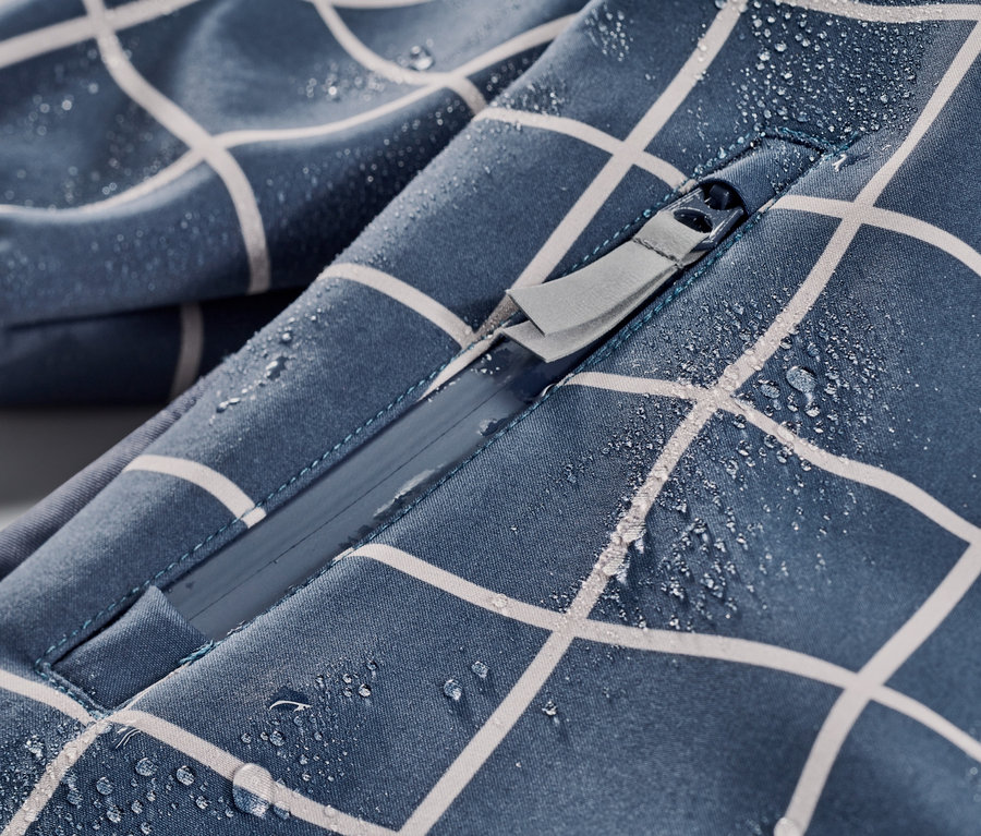 Zbliżenie na dziecięcy kombinezon softshell w kratkę z zamkiem błyskawicznym i kroplami wody.