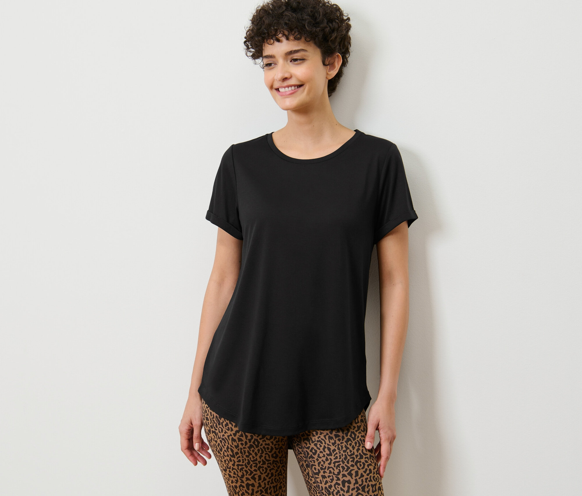 Kobieta pozuje w czarnej długiej koszulce.