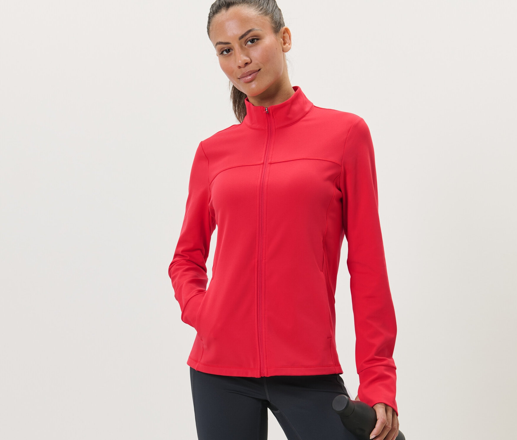 Kobieta ma na sobie czerwoną rozpinaną bluzę sportową.