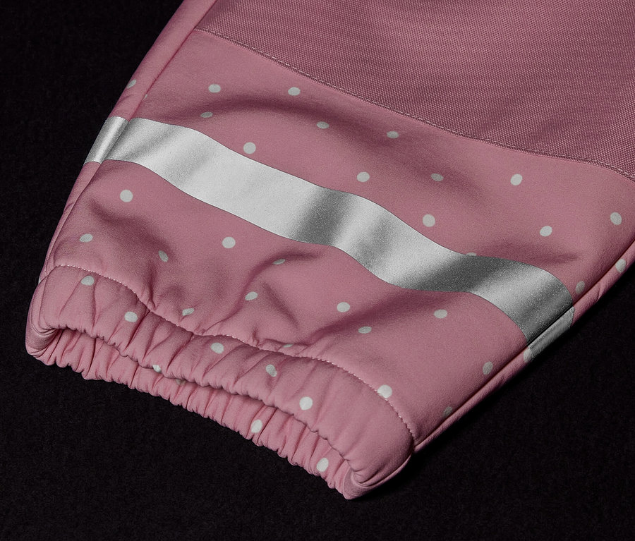 Zbliżenie na kombinezon softshellowy dla dzieci z różowym rękawem, białymi kropkami i odblaskowym paskiem.