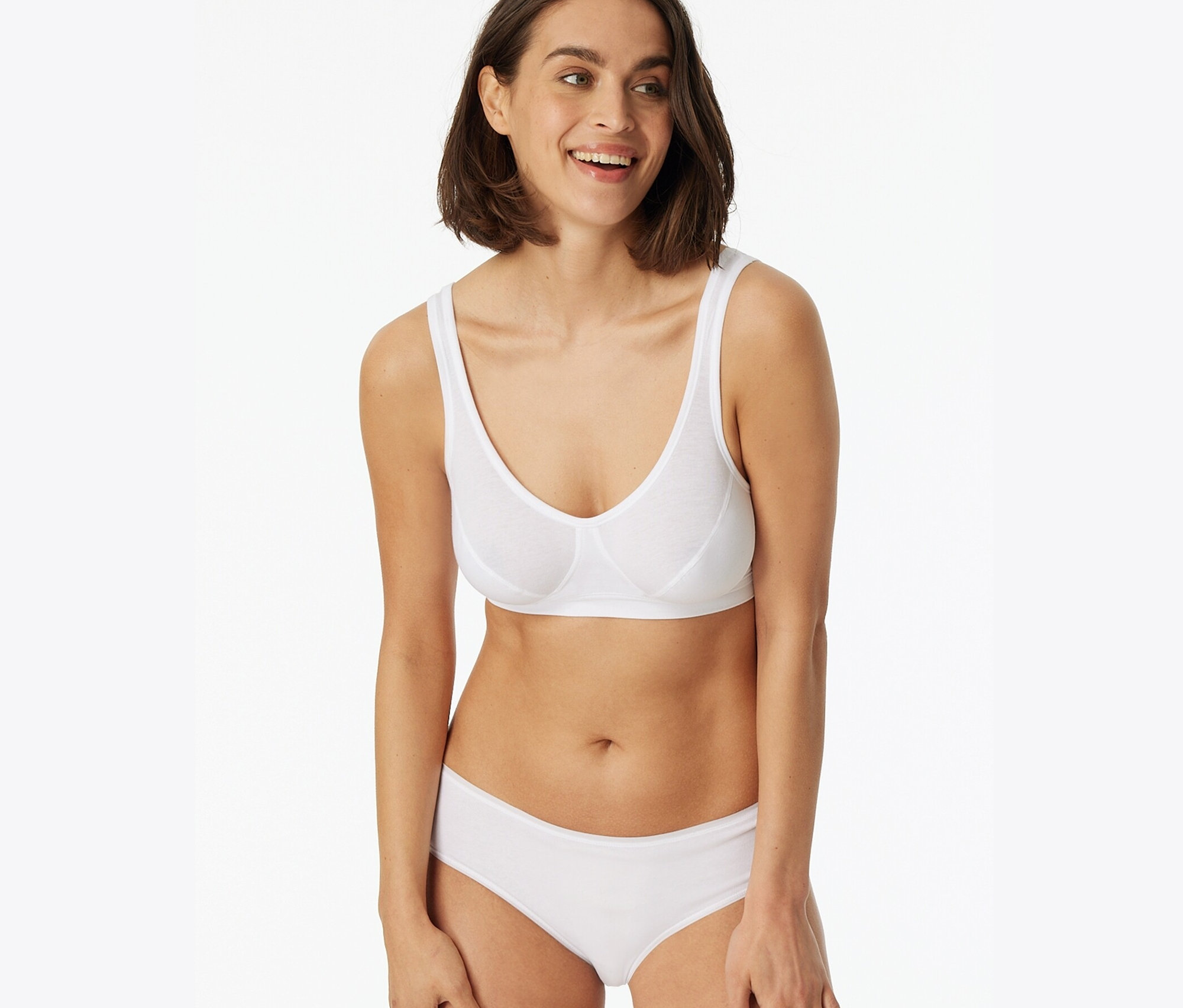 Uśmiechnięta kobieta ma na sobie biały biustonosz i figi SCHIESSER, 2 pary, białe.