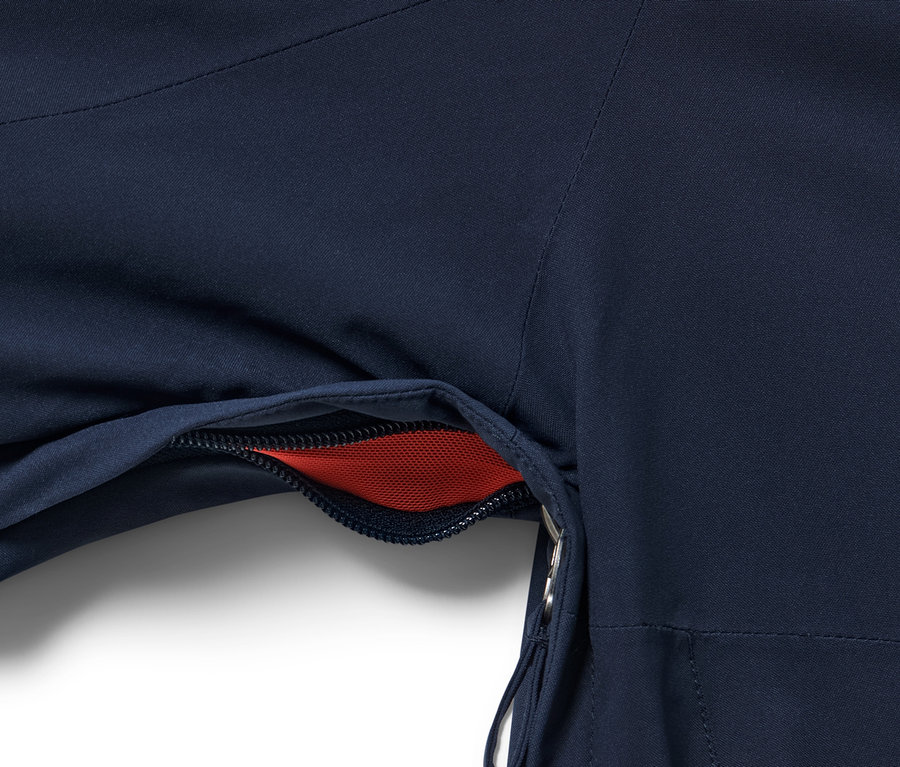 Zbliżenie na niebieską kurtkę narciarską High Tech z otwartą kieszenią, w której widać czerwoną siatkę.