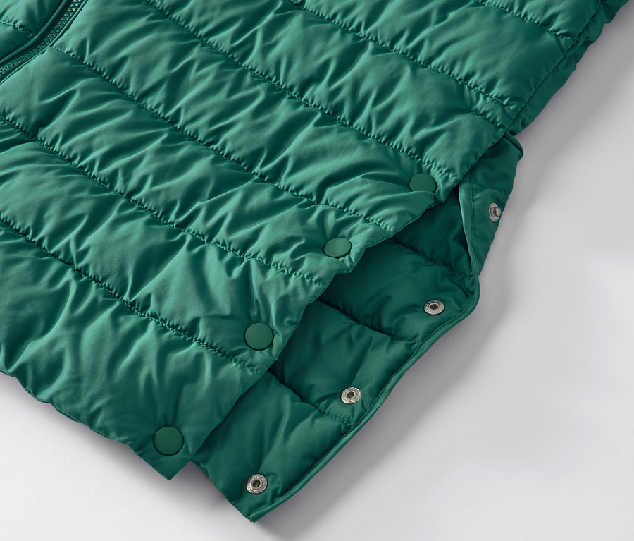 Zbliżenie na zielony pikowany płaszcz z kapturem zapinany na zatrzaski.