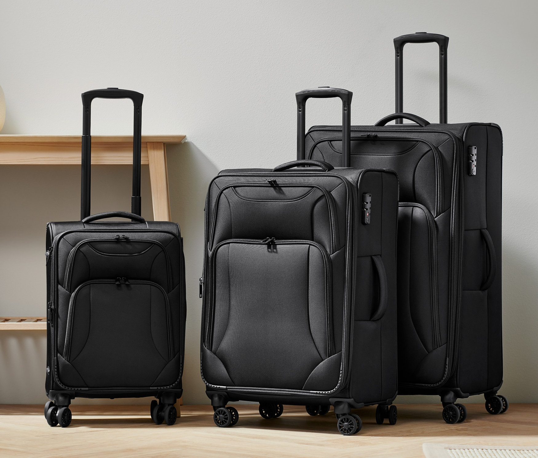 Trzy walizki tekstylne w różnych rozmiarach (mała, średnia i duża) stoją obok siebie.