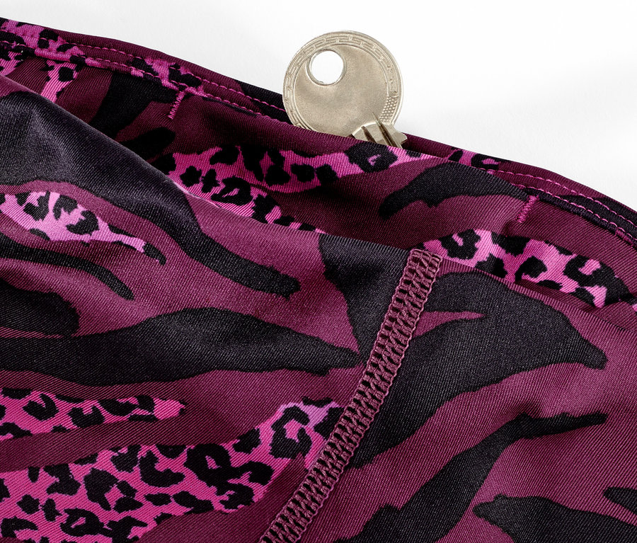 Zbliżenie na fioletowe legginsy sportowe 3/4 z nadrukiem na całej powierzchni i kluczem w kieszeni.