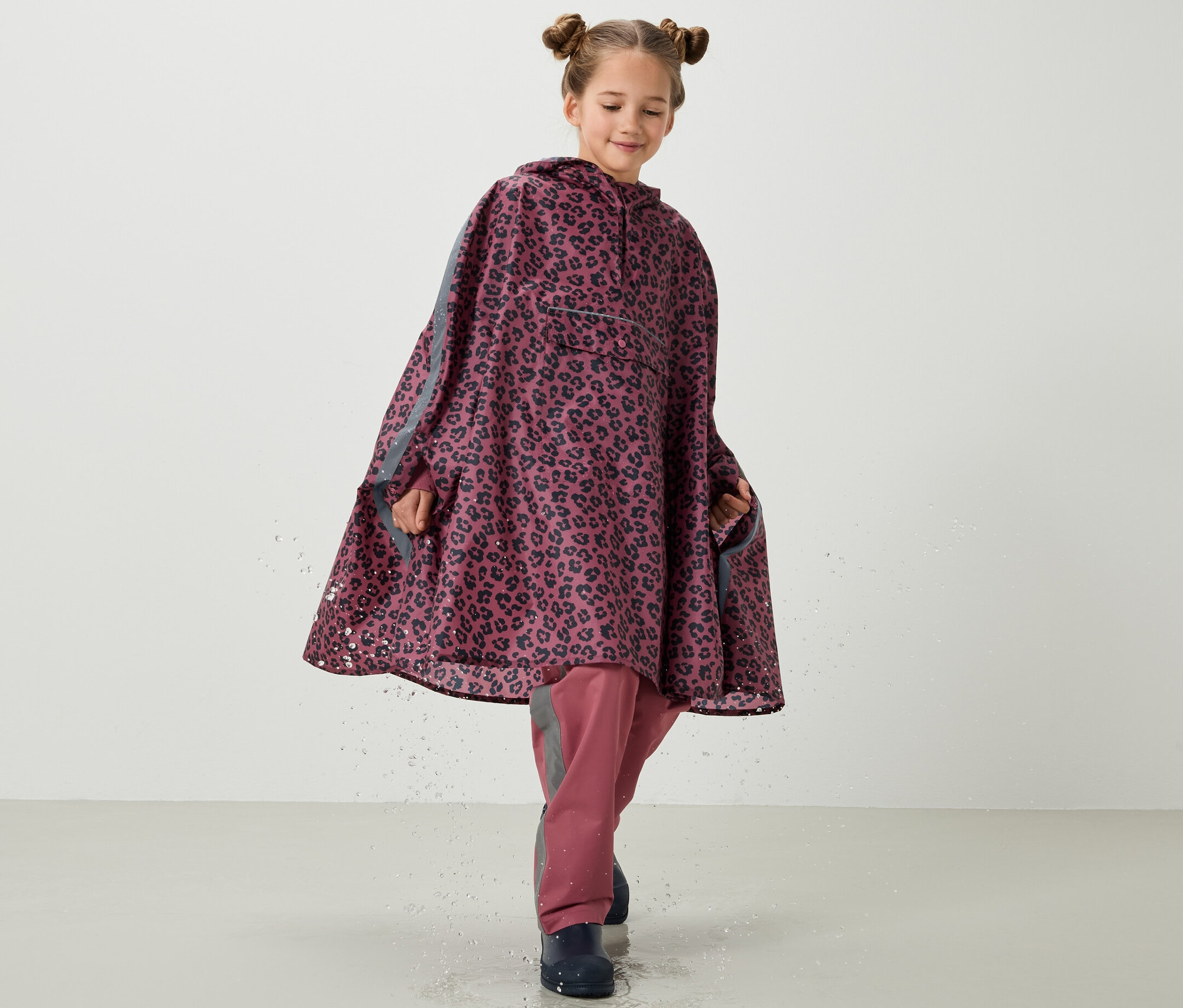 Dziewczynka w różowym ponczo przeciwdeszczowym z nadrukiem na całej powierzchni.