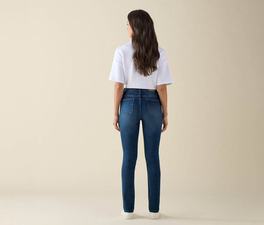Kobieta stojąca tyłem w dżinsach slim fit »Emma« w kolorze niebieskiego denimu i białym t-shircie.