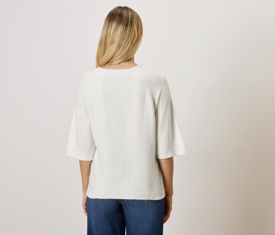 Widok z tyłu kobiety z blond włosami w białej bluzce i niebieskich dżinsach.