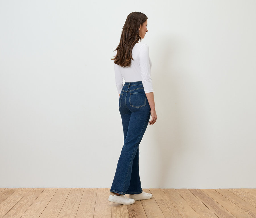 Kobieta pozuje w dżinsach i białym topie.