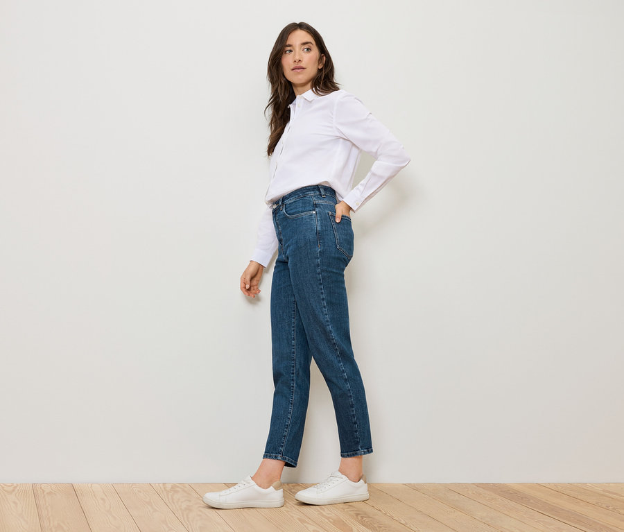 Kobieta pozuje w niebieskich Mom Jeans – Fit »Nyla« i białej koszuli.