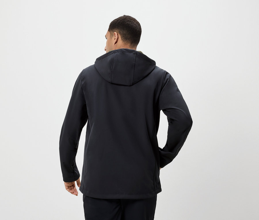 Mężczyzna tyłem do kamery ubrany w czarną kurtkę z kapturem.