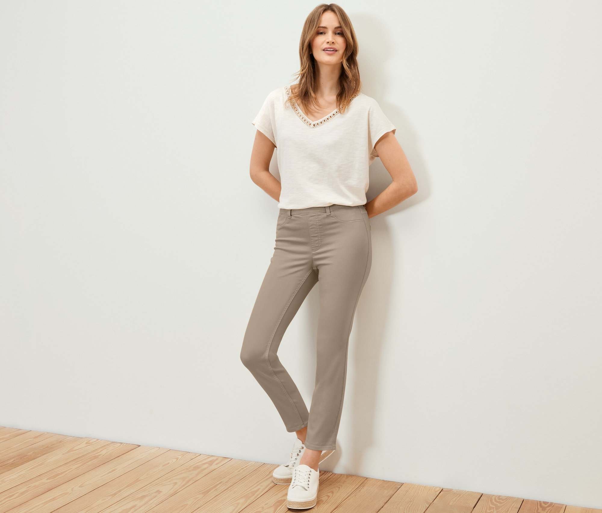 Kobieta pozuje w tregginsach o długości 7/8, koszulce i trampkach.